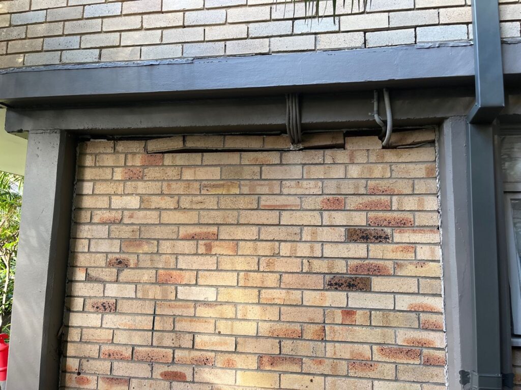Cracked brickwork and gaps under a beam caused by ground movement