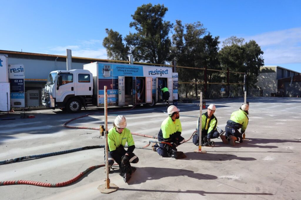 Resinject crew injecting resin into a commercial slab while monitoring levels